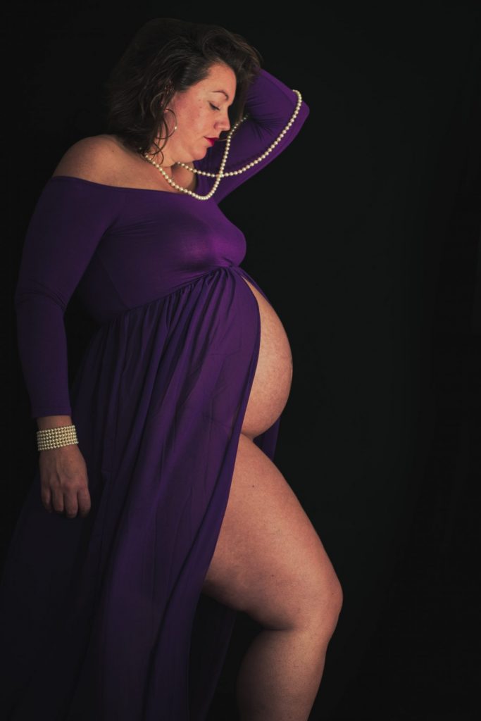 Future maman en robe violette pendant sa séance photo